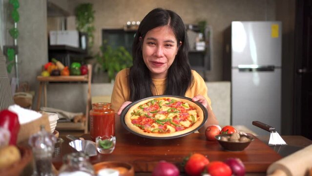 Asian beautiful woman baking a pizza and making a video live streaming on social network.