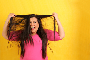 Adult 40-year-old Latina woman ruffles her hair desperate with anxiety and frustration with very...
