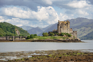 Fototapeta na wymiar Eilean Donan Castle showcased on a picturesque cloudy day, embodying the charm of Scotland's scenic beauty.