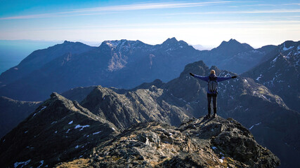A hiker admiring the scenic snowy Cuillin Mountains on the Isle of Skye, Scotland.