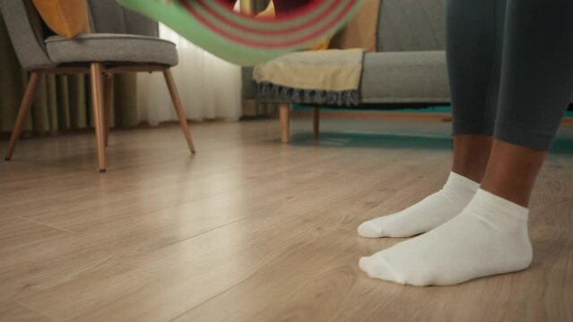 African American woman getting ready for workout at home. Woman's legs in white socks close up. A woman lays out a sports mat on the floor in the living room. Slow motion.
