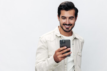 Close-up portrait man holding a phone smile typing a message, chatting online freelance work on a white isolated background, fashionable clothing style, copy space, space for text