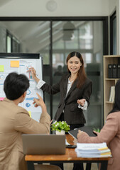 Asian business presents to explain the graph work on the whiteboard. Consulting, discussing, exchanging knowledge.