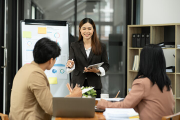 Asian business presents to explain the graph work on the whiteboard. Consulting, discussing, exchanging knowledge.