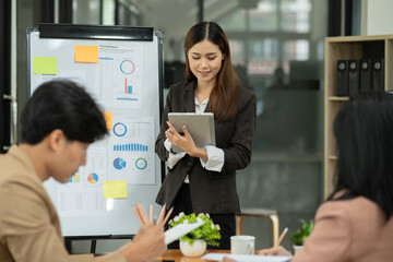 Asian business presents to explain the graph work on the whiteboard. Consulting, discussing, exchanging knowledge.