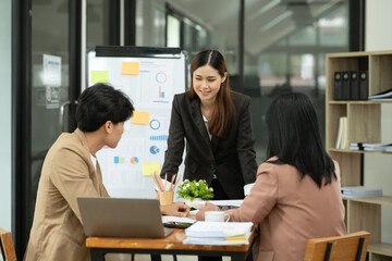 Asian business presents to explain the graph work on the whiteboard. Consulting, discussing, exchanging knowledge.