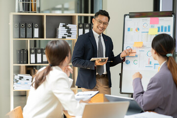 Fototapeta premium Asian business presents to explain the graph work on the whiteboard. Consulting, discussing, exchanging knowledge.