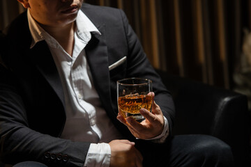 Businessman sitting Holding a Glass of Whiskey Drink Whiskey in the liquor store room