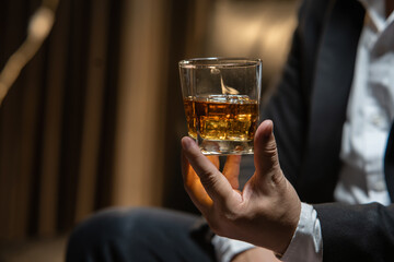 Businessman sitting Holding a Glass of Whiskey Drink Whiskey in the liquor store room