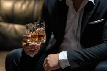 Businessman sitting Holding a Glass of Whiskey Drink Whiskey in the liquor store room