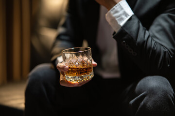 Businessman sitting Holding a Glass of Whiskey Drink Whiskey in the liquor store room