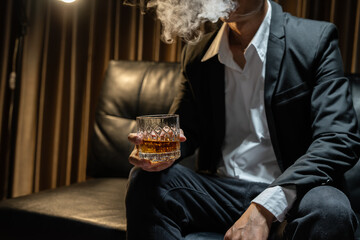 Businessman sitting Holding a Glass of Whiskey Drink Whiskey in the liquor store room