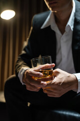 Businessman sitting Holding a Glass of Whiskey Drink Whiskey in the liquor store room