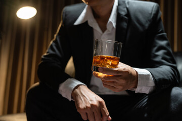 Businessman sitting Holding a Glass of Whiskey Drink Whiskey in the liquor store room