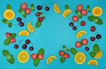  fruit set with fresh cherries, mint leaves, slices of strawberries and oranges  on  bright  blue background with free space in the center .Frame with fresh fruits and berries.Top view, flat lay.