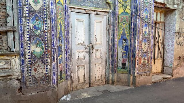 Walking tour in walkway in Rasht old city town in front of an Persian ancient colorful historical workshop landmark gate with blue tiles wall of love fame in down town in a farmer local people market
