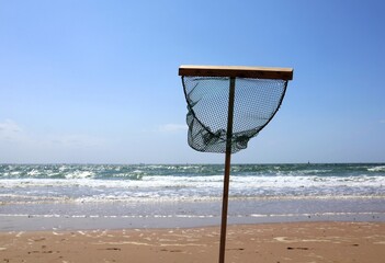 Shrimp net stands on the beach. Push net or landing net. Summer vacation concept.