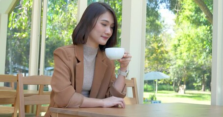 Asian Woman drink black coffee hand holding cup at green garden cafe. Young woman smile face love drink coffee. Beauty woman drinking black tea in coffee cafe shop holding fresh cup. Women lifestyle