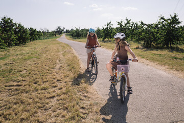 Obraz premium two sisters ride a bike, orchard cherry orchard, country life