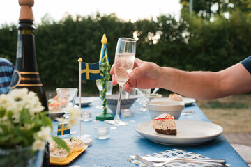 Obraz na płótnie Canvas man holding champagne glass celebrating midsummer in Sweden