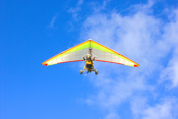Fototapeta na wymiar On a clear sunny day, a hang glider flies high in the sky.