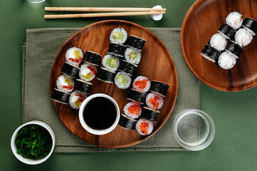Sushi and soy sauce in a bowl and wooden chopsticks on a gray wo