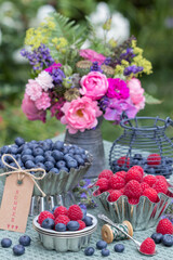 Tisch-Arrangement mit frischen Himbeeren und Heidelbeeren in vintage Backformen 