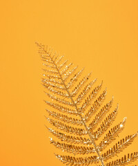 A beautiful shining branch of gold color on a yellow background for interior decorating.