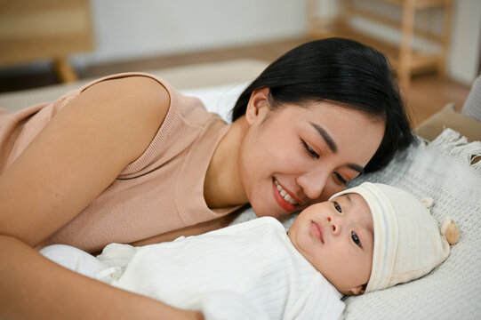 Beautiful Asian Mom Lay Down With Her Baby, Comforting Her Son On Bed.