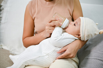 Obraz na płótnie Canvas Mother holding and feeding baby from milk bottle. cute newborn baby