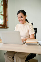 Young beautiful Asian woman working in her home office with laptop