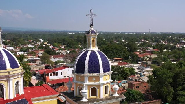 Toma de drone que gira sobre las cupulas de la Parroquia San Francisco de Asisi mostrando el pueblo a su alrededro, Colima.
