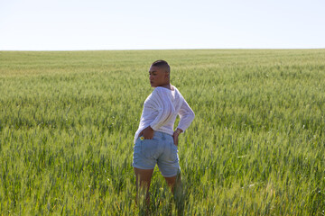 Naklejka na ściany i meble Non binary latin person and young gay man having fun in the green wheat field doing different back body postures. Concept of ecological agriculture, homosexuality and human rights.