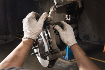 An auto mechanic maintains the brake system of a car, after installing a new brake disc, tightens the bolts