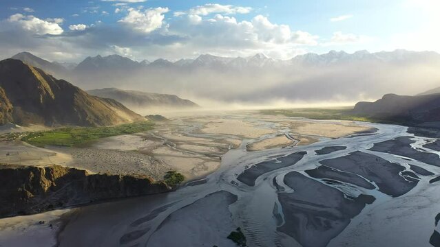 Cinematic aerial shot of Skardu Valley in Gilgit Baltistan, Pakistan. Wide slowing rotating, into the sun, and over water in the valley. Shigar and Indus River. Epic drone shot.