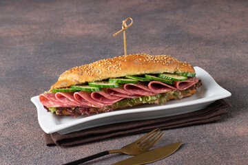 Homemade sandwich with sausage, cucumber, melted cheese and lettuce