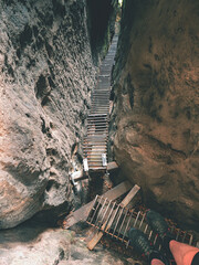 Steel path like steps and ladder in thin gulch between sandstone rocks.