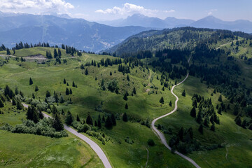 Fototapeta na wymiar Aerial view of meandering roads vantage viewpoint lookout in mountains of French Alps with Mont Blanc Massive and eternal snow tops in the background. Tourism and outdoor sports ski holidays region.