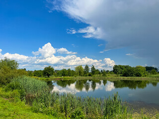 A beautiful small lake in the countryside. Sunny day with clouds in the sky. Perfect place for relaxing