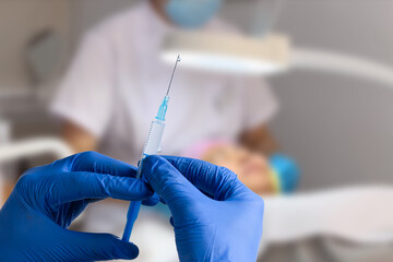 Cosmetologist in sterile gloves holds syringe for injection with collagen hyaluronic filler for face or lips rejuvenation, close up.