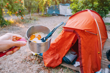 freeze-dried camping food - rice with dried fruits in a pot on the background of a tent in a camping - obrazy, fototapety, plakaty