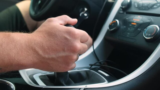The male driver switches the automatic transmission in the car. Close-up.