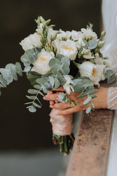 Wedding portrait. A brunette bride in a long dress holds her bouquet of roses, peonies and greenery. Cropped photo.
