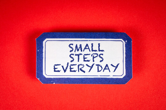 SMALL STEPS EVERYDAY. Sticky note with text on a red background