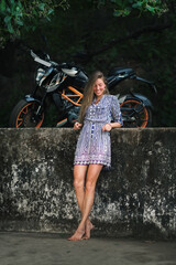 Naklejka premium Stylish Woman Posing Near a Motorcycle Outdoors.