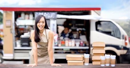 happy asian woman start new business food truck serving with box and cup for take away clients on blur food truck background