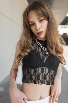 Street stylish portrait of a beautiful fashionable girl with Jewellery in a fashion black lace top and bra walks in the city
