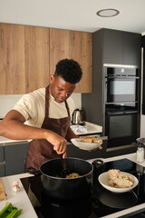 Fototapeta na wymiar Young black man preparing fried chicken mince with vegetables recipe in a kitchen.