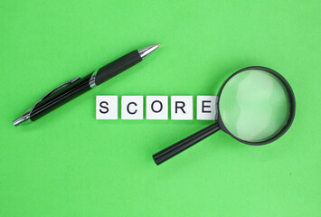 pen, alphabetical magnifying lens with a score word. the concept of target or score