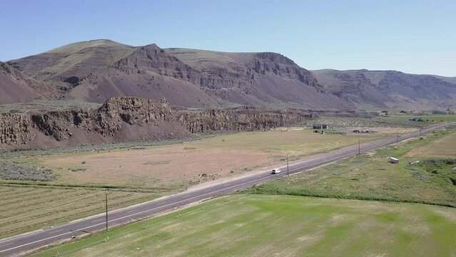 Aerial tracks white van driving in scenic scablands coulee bottom